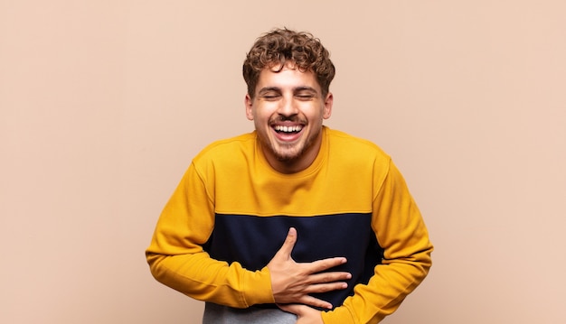 Young man laughing out loud at some hilarious joke, feeling happy and cheerful, having fun