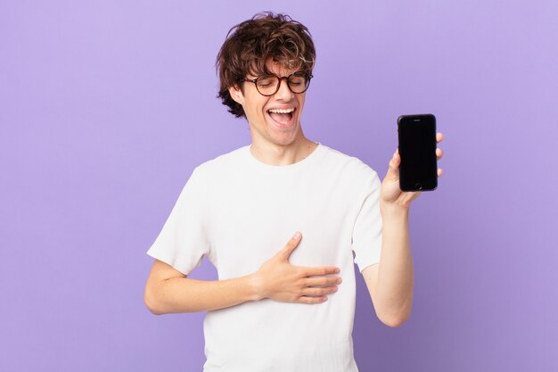 Young man laughing out loud at some hilarious joke and holding a cell