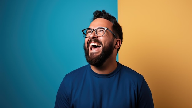 Young man laughs against a blue background