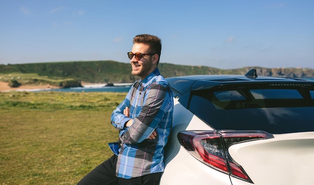 Young man leaning on his car