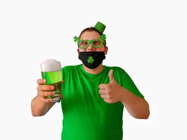 レプラコーンの帽子をかぶった若い男が聖パトリックの日を祝うアイルランド人が緑色のビールを飲む