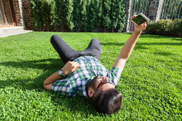 若い男は芝生に横になり、夏を楽しんでいます