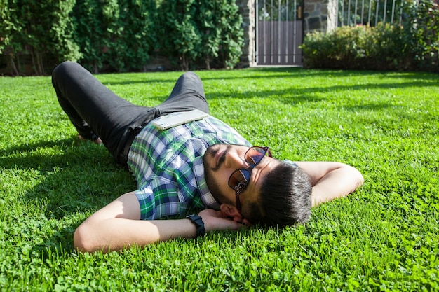 若い男は芝生に横になり、夏を楽しんでいます