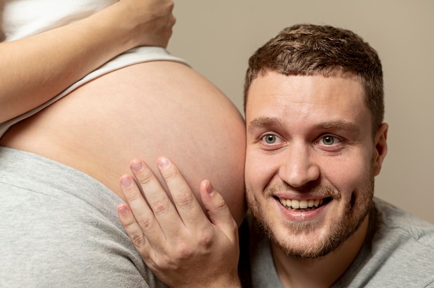 妊娠中の妻の腹を聞いている若い男性