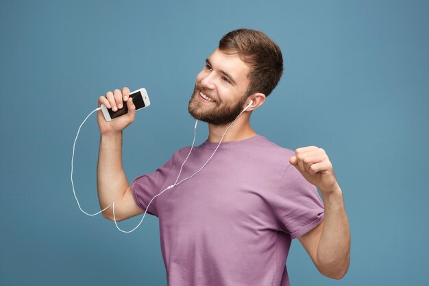 Young man listening to music against color background