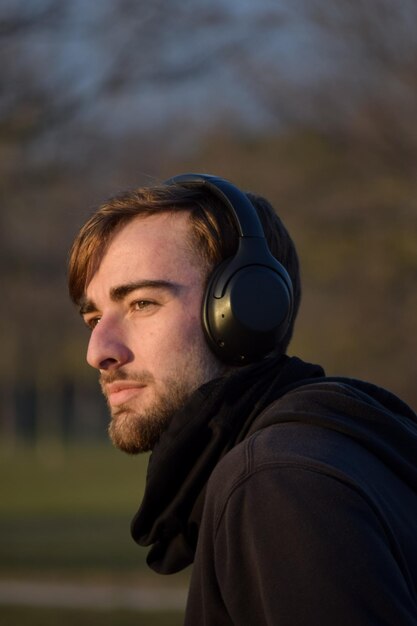 Young man listening music on headphones at the sunrise