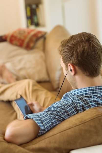 Young man listening to music on his couch 