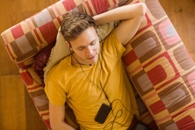 Photo young man listening to music on his couch