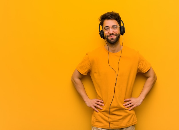 Photo young man listening to music with hands on hips