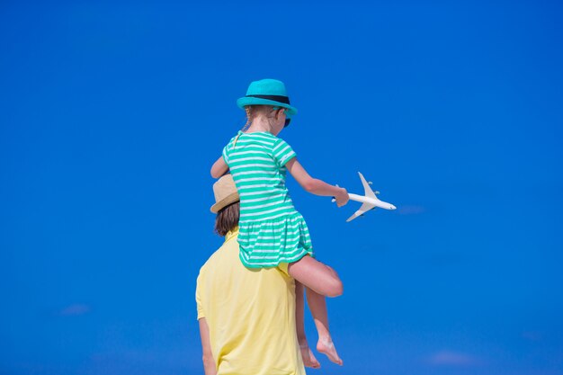 Young man and little girl with miniature of airplane at beach