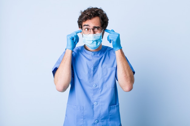 Young man looking angry, stressed and annoyed, covering both ears to a deafening noise, sound or loud music. coronavirus concept