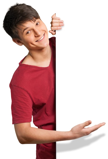 Young man looking around a corner and showing off a blank sign