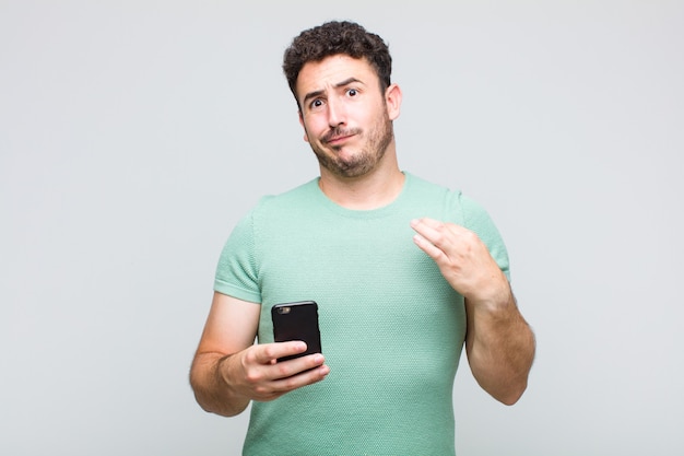 Young man looking arrogant, successful, positive and proud, pointing to self