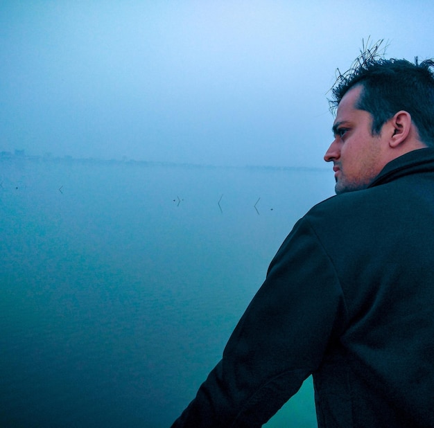 Фото Молодой человек смотрит на море в туманную погоду