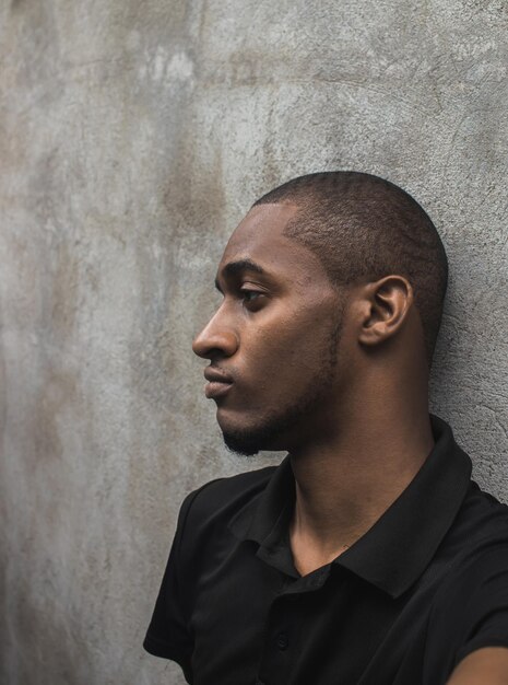 Young man looking away against wall