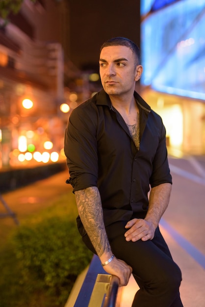 Young man looking away in city at night