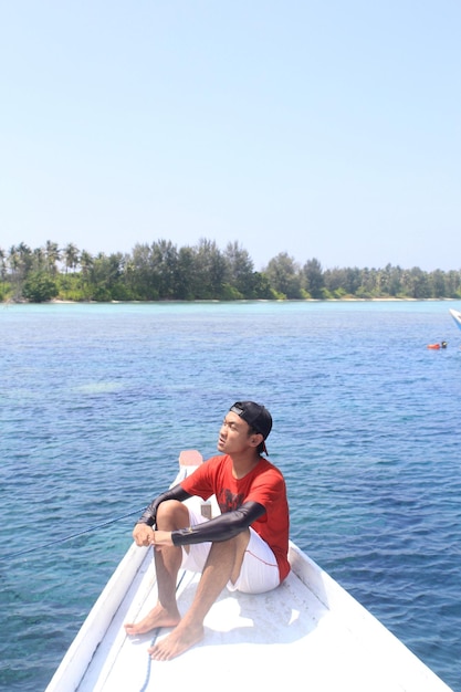 Young man looking away sitting on rowboat in lake