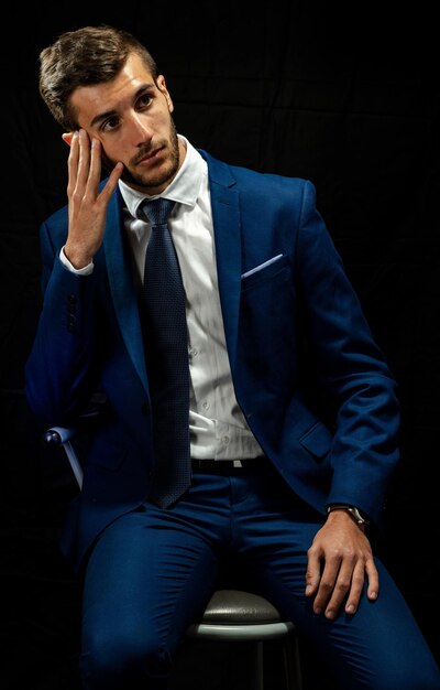 Photo young man looking away while sitting against black background