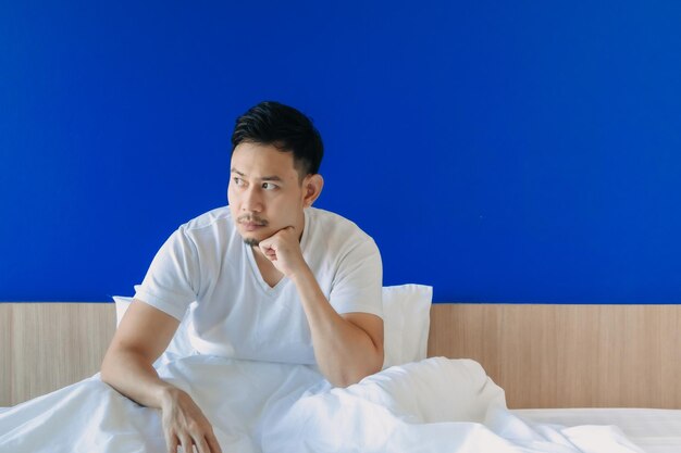 Young man looking away while sitting on bed