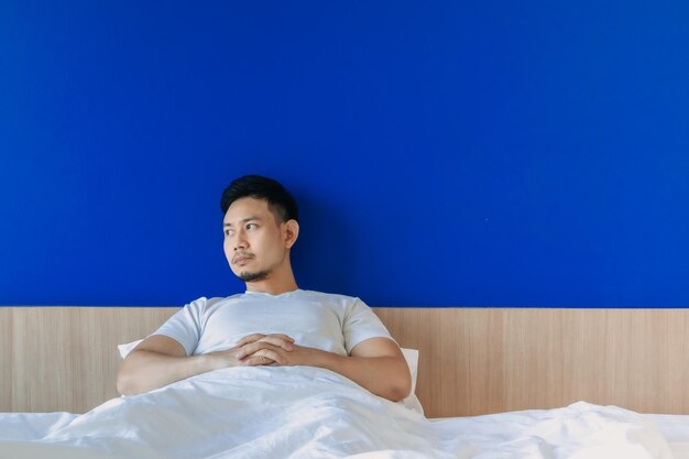 Young man looking away while sitting on bed