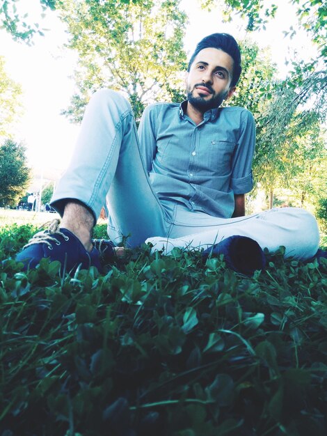 Young man looking away while sitting on field