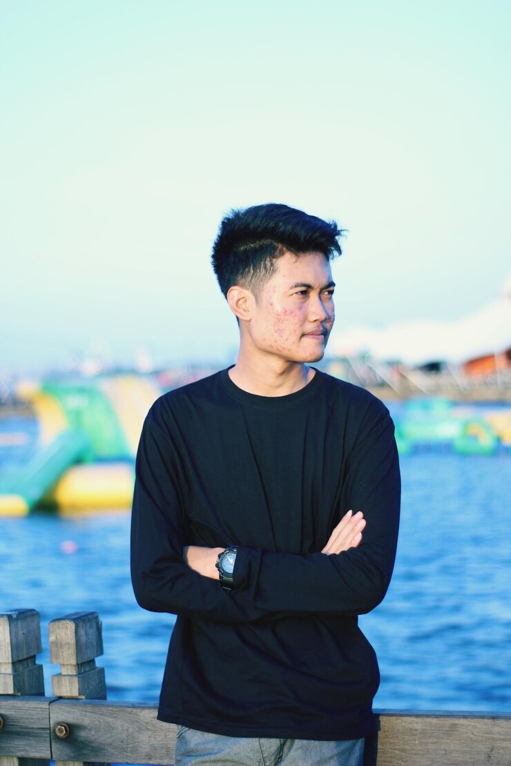 Photo 海に向かって立っている若い男が目をそらしている