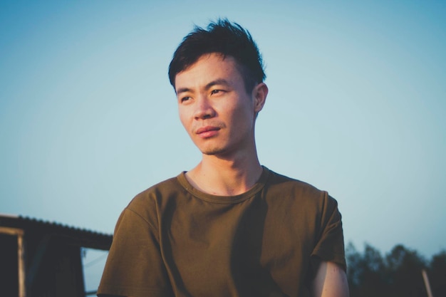 空に向かって立っている若い男が目をそらしている