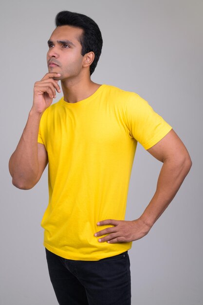 Young man looking away while standing against white background