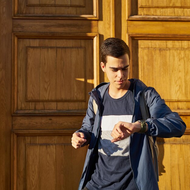 Photo young man looking away while standing against wooden wall