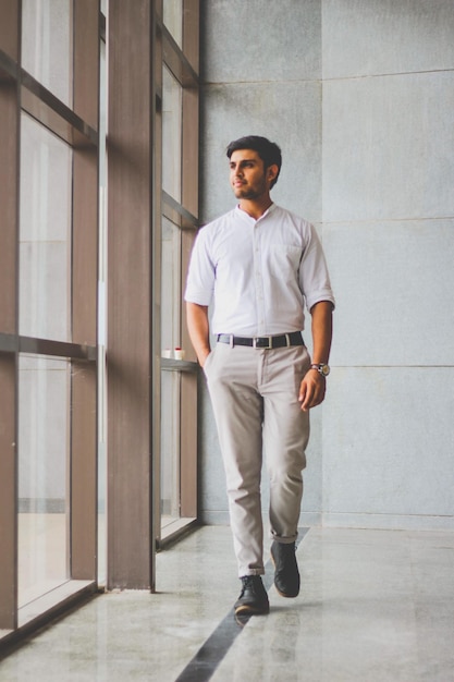 Young man looking away while standing by wall