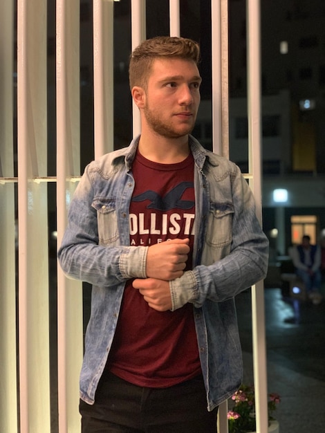 Photo young man looking away while standing in city at night