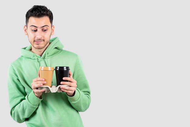 young man looking at coffee cups in his hands