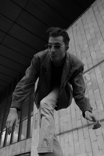 壁に寄りかかって床に立っている若い男が下を見下ろしている