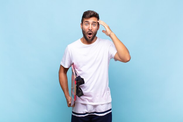 Young man looking happy, astonished and surprised, smiling isolated