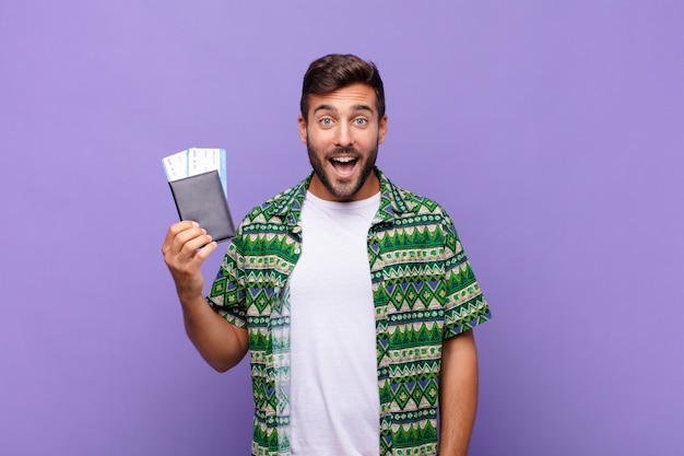 Young man looking happy and pleasantly surprised, excited with a fascinated and shocked expression.