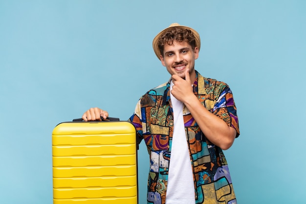 Young man looking happy and smiling with hand on chin, wondering or asking a question, comparing options