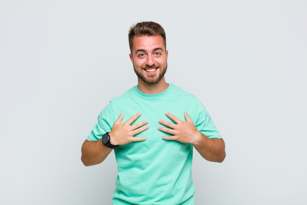 Young man looking happy, surprised, proud and excited, pointing to self