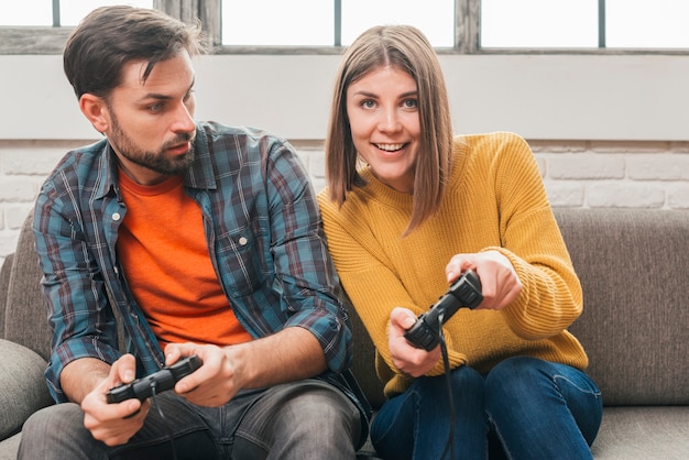 Young man looking at her girlfriend playing the video game with joystick