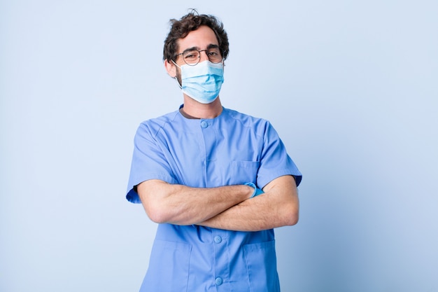 Young man looking like a happy, proud and satisfied achiever smiling with arms crossed. coronavirus concept