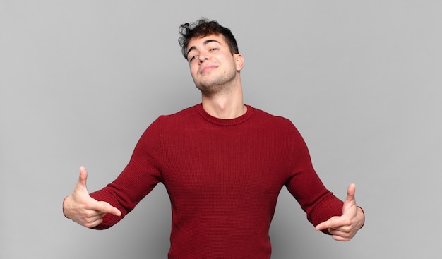 Young man looking proud, arrogant, happy, surprised and satisfied, pointing to self, feeling like a winner