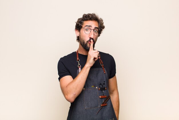 Young man looking serious and cross with finger pressed to lips demanding silence or quiet, keeping a secret