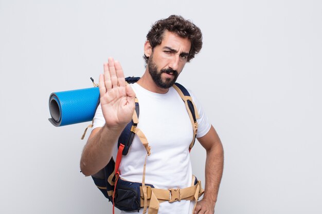 Young man looking serious, stern, displeased and angry showing open palm making stop gesture