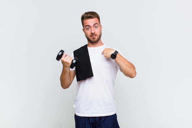 Young man looking shocked and surprised with mouth wide open