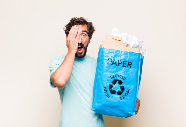 Young man looking sleepy, bored and yawning, with a headache and one hand covering half the face