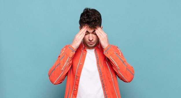 Young man looking stressed and frustrated, working under pressure with a headache and troubled with problems