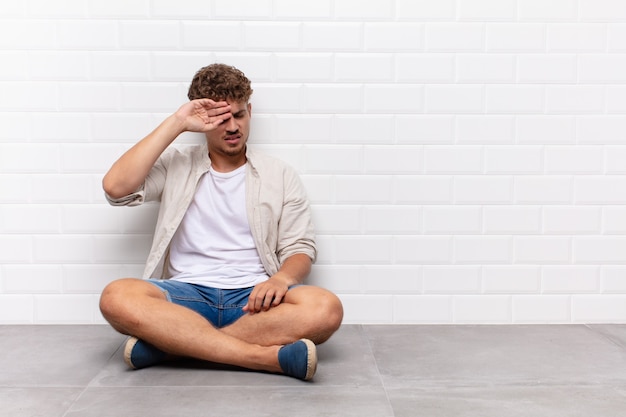 Young man looking stressed, tired and frustrated, drying sweat off forehead, feeling hopeless and exhausted