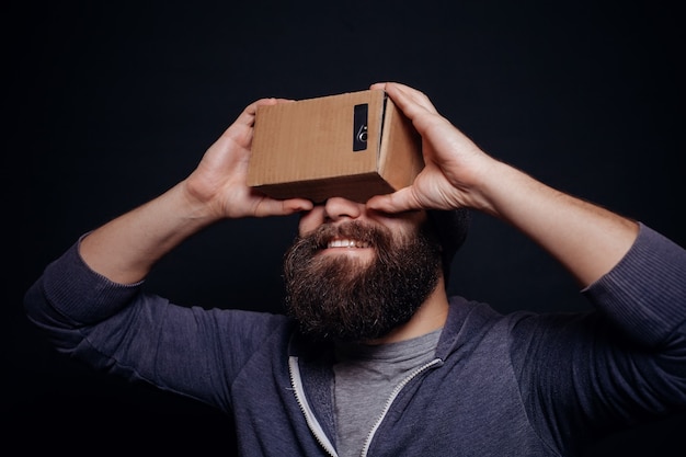 Young man looking through cardboard VR headset