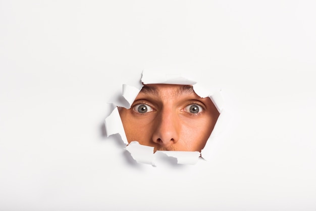 Young man looking through paper rip