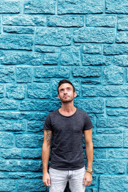 Photo young man looking up while standing against wall