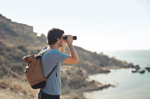 young man looks for a target with binoculars